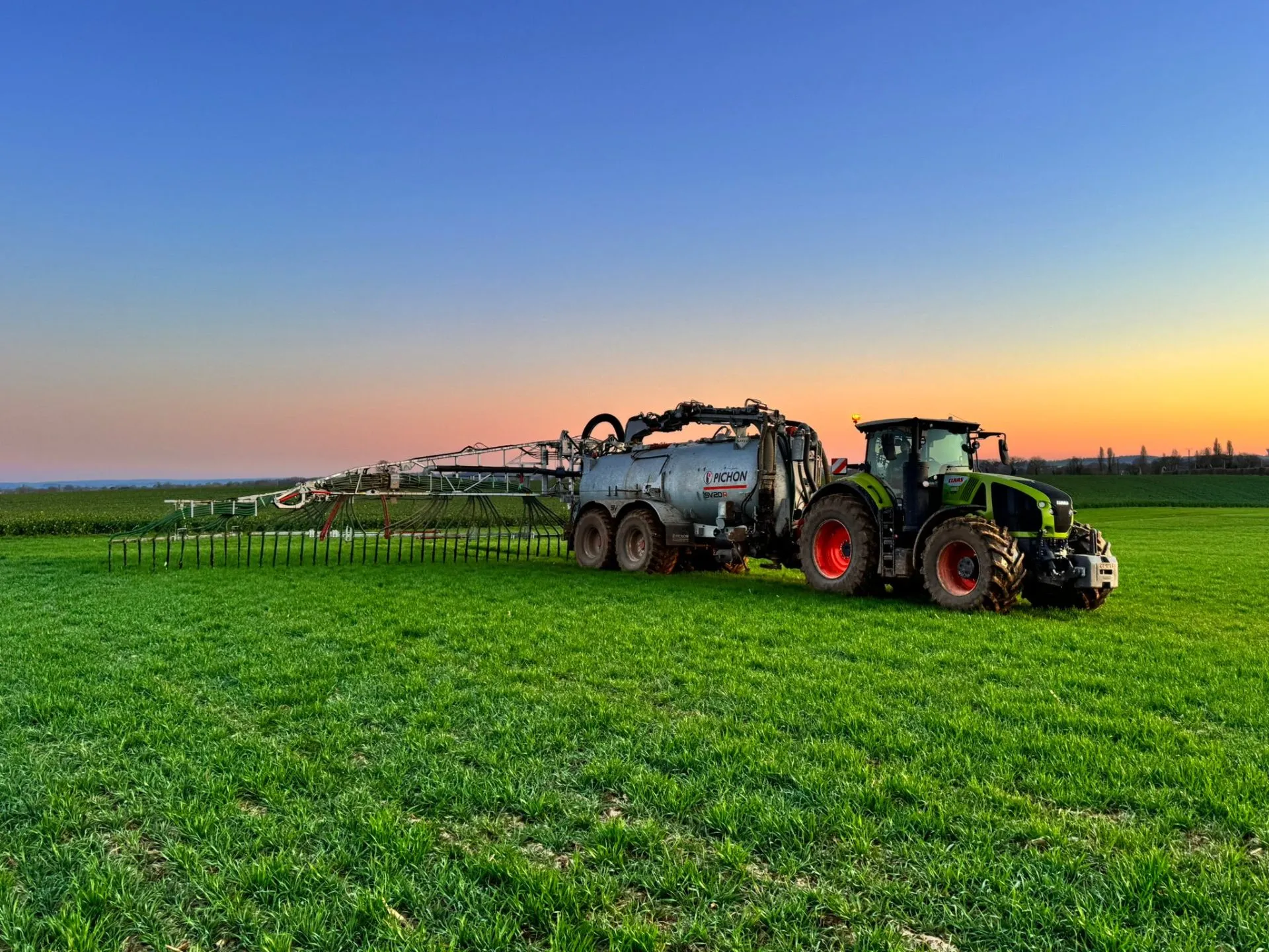 Tracteur agricole épandant du digestat au coucher du soleil